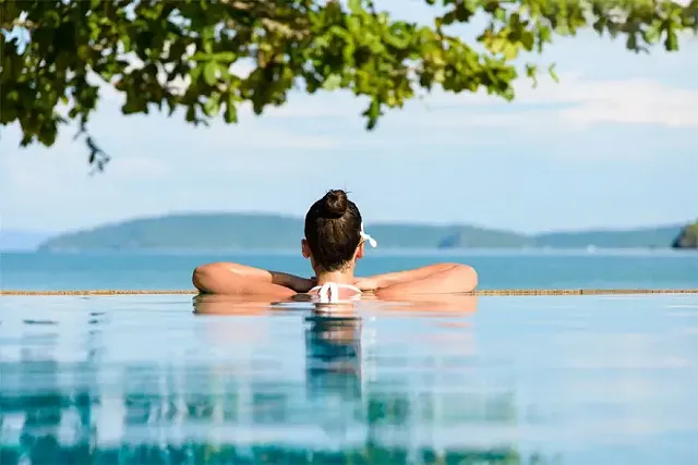 a man sat in an infinity pool looking out over the landscape